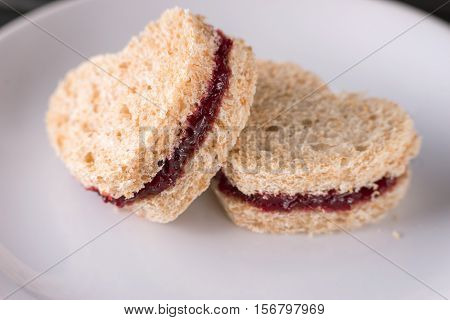 Sweet sandwiches cut in heart shape with red plum jam for Valentine's day