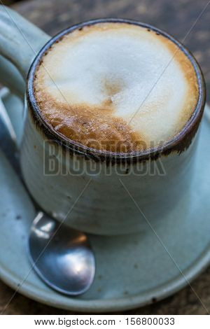 A cup of hot cappuccino coffee on the table wood.