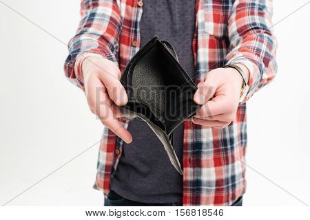 Closeup image of a man in plaid shirt holding emty wallet over white background