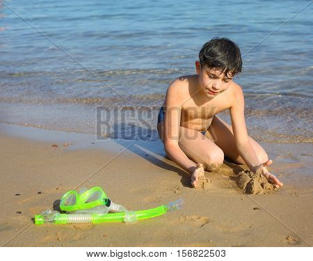 preteen handsome boy with snorkeling mask and tube on the red sea beach background