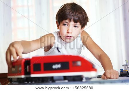 preteen handsome boy play with meccano toy train and railway station