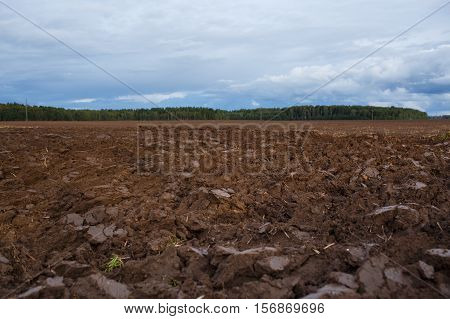 plowed field with tractor traces in spring time, farm soil background.