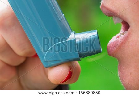 closeup of woman with asthma aerosol with greenery background