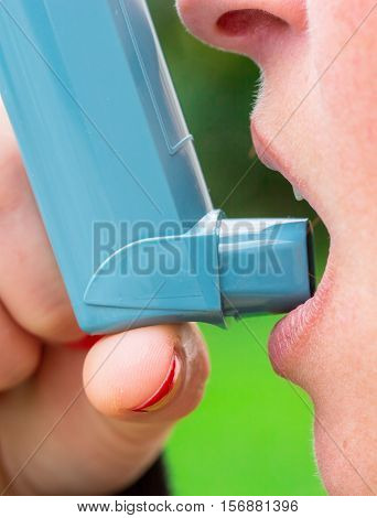 closeup of woman with asthma aerosol with greenery background
