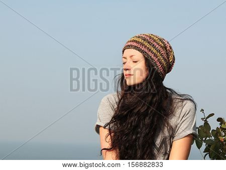 young woman with eyes closed breathing fresh air on sea background
