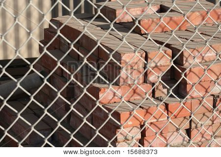 A stack of bricks behind a fence