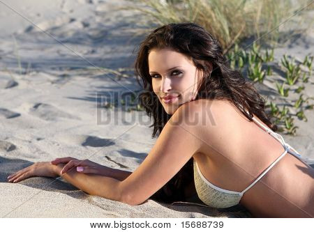 Beautiful model on the beach laying in the sand