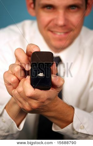 A man proposing and holding up an engagement ring