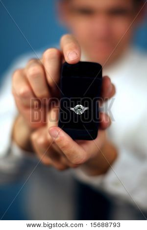 A man proposing and holding up an engagement ring