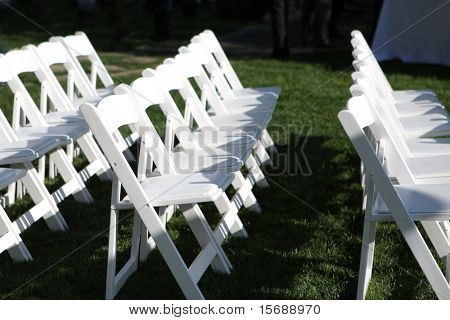 Weiße Stühle auf eine Hochzeit im freien einrichten