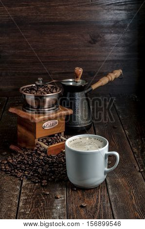 Coffee Cup With Beans, Grinder And Jezve On Dark Background