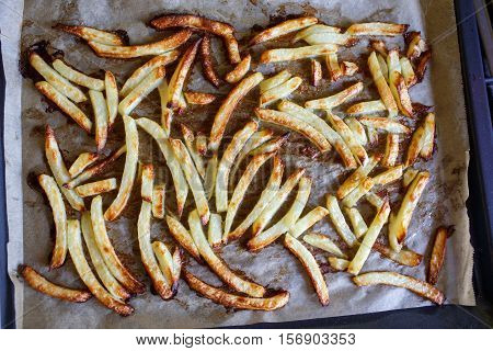 Potato fries on baking plate and paper