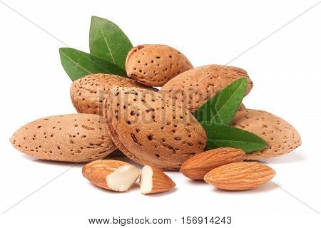 heap of almonds in their skins and peeled with leaf isolated on white background.