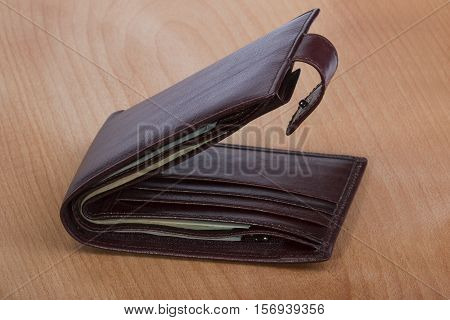 brown leather men's wallet with money on a wooden background