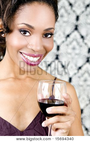 Belle femme noire tenant un verre de vin rouge
