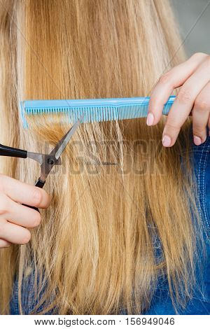 Cutting down and shearing concept. Blonde woman cuts and combing her straight smoothy fair hair. Professionalist making new coiffure hairdo.