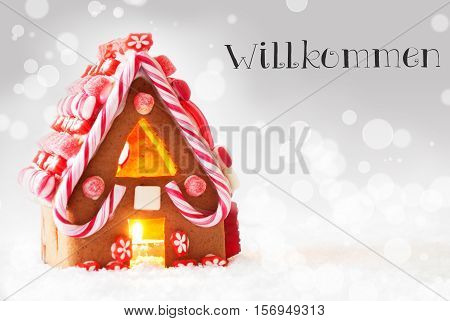 Gingerbread House In Snowy Scenery As Christmas Decoration. Candlelight For Romantic Atmosphere. Silver Background With Bokeh Effect. German Text Zauberhafte Weihnachten Means Magic Christmas