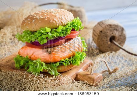 Tasty Fishburger With Salmon On Old Wooden Table