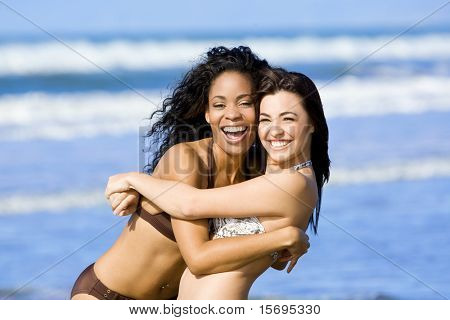 Dos amigos diversos felices jugando en la playa