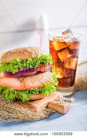 Tasty Fishburger With Salmon Served With Cold Drink On Old Wooden Table