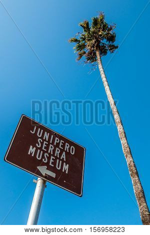 SAN DIEGO, CALIFORNIA - AUGUST 13, 2016:  Sign marker for the Junipero Serra museum, the site of the first permanent European settlement, with a Washingtonia robusta palm tree in the background.