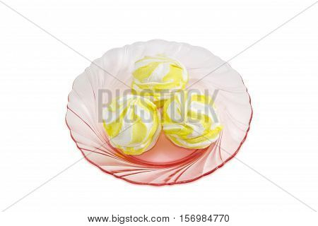 Three soft confectionery - zefir white and yellow color on a pink glass dish on a light background
