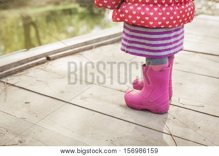 little girl in rainboots in autumn or winter nature, kids seasonal activities
