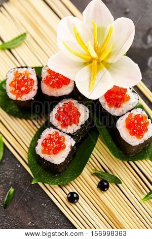 Ikura Maki Sushi - Roll with Cream Cheese inside. Topped with Ikura (Salmon Roe). Sushi Food and Natural Flower Concept