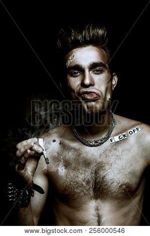 Antisocial behavior, bad habits. Portrait of a bad boy smoking cigarette. Rocker, punk.