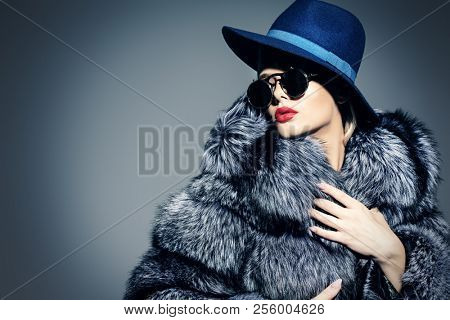 Beautiful woman in luxurious fur coat posing in studio. Luxury, rich lifestyle. Fashion shot. 