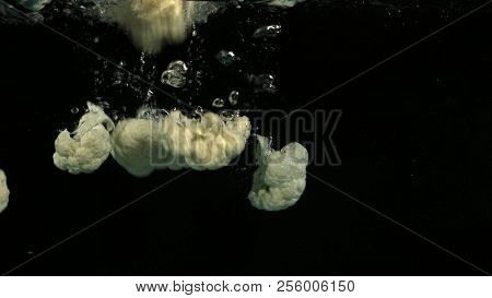 Cauliflower falling into water on black background. Bright high quality video. Shot 120 frames per second on BlackMagic URSA camera.