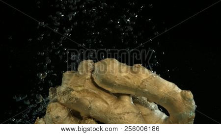 Ginger falling into water on black background. Bright high quality video. Shot 120 frames per second on BlackMagic URSA camera.