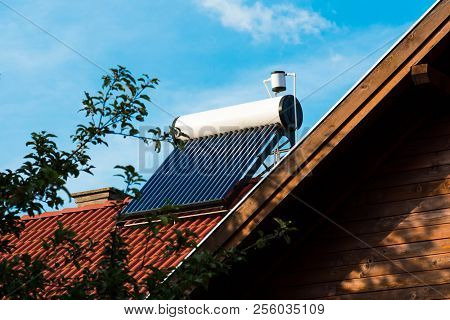 Solar Water Heater Boiler Close Up Shot On Residentual House Rooftop, Blue Sky Background.
