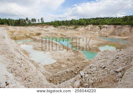 Kaolin clay quarry open pit at summer day with blue water