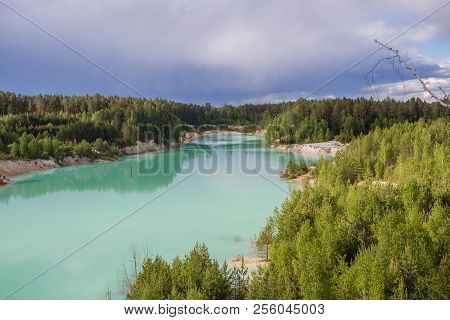 Kaolin clay quarry open pit at summer day with blue water