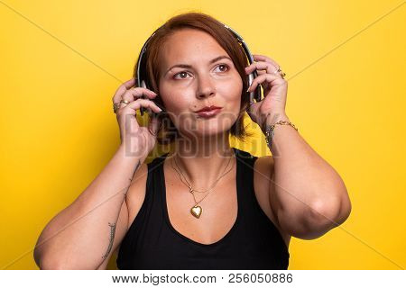 Wouman Touching Wireless Headphones While Looking Away