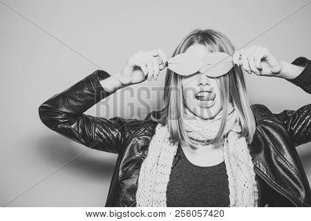 Woman With Autumn Leaves As Glasses In Leather Jacket And Scarf On Orange Background Show Tongue
