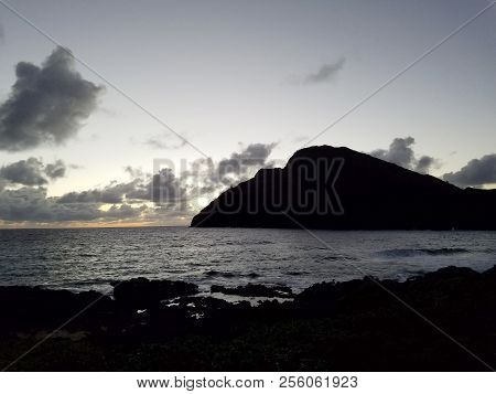 Ocean Waves Lap On Makapuu Beach Before Dawn With Makapuu Lighthouse And Point In The Distance Looki