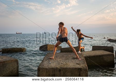 Gizelle-dere Village, Russia, August 07, 2018: Two Boys Jumping On Concrete Blocks On The Seashore