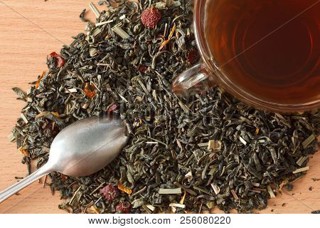 Background With Green Tea. Cup With Tea And Dried Green Tea Leaves On The Table. Spilled Tea Leaves 