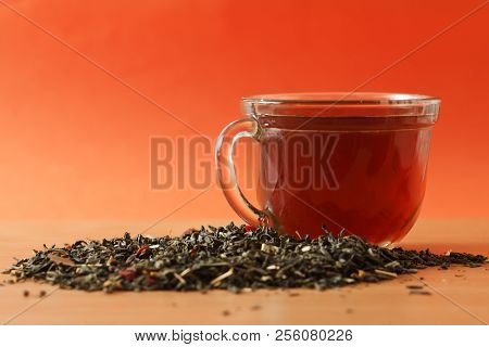 Background With Green Tea. Cup With Tea And Dried Green Tea Leaves On The Table. Spilled Tea Leaves.