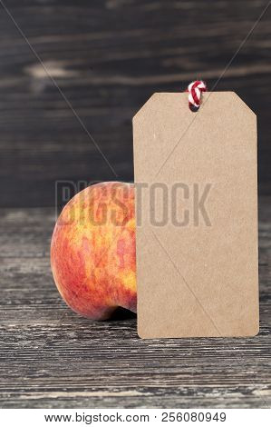 One Ripe Orange Peache Of A Large Size, On Peaches There Is A Wooden Label For The Price Or Another 