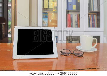 Mock Up Image Of White Tablet Pc With Black Blank Screen And Coffee Cup On Wooden Table In Blur Offi