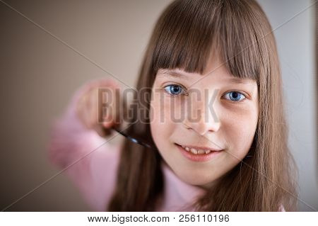 Little Girl With Freckles And Blue Eyes Combing Her Hair