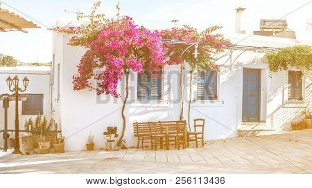 Beautiful narrow street with white houses in Mikonas island, Greece. Traditional narrow street with white facedes of buildings and blue doors