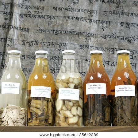 medicina cinese erbe e intrugli in bottiglie grandi su sfondo scrittura tibetana