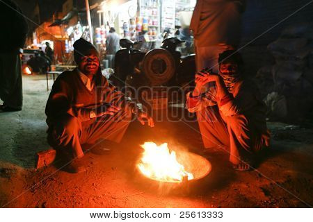 DELHI - 11 februari: Män sitter runt gatan eld på natten den 11 februari, 2008 i Delhi, Indien. W