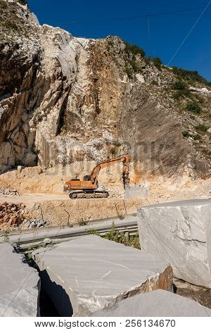 Orange Tracker Excavator With The Jackhammer In A Marble Quarry (carrara White Marble) In The Apuan 
