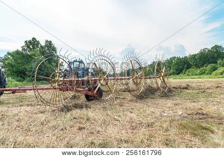 Tedders For Hay In The Meadow In The Background Of The Forest