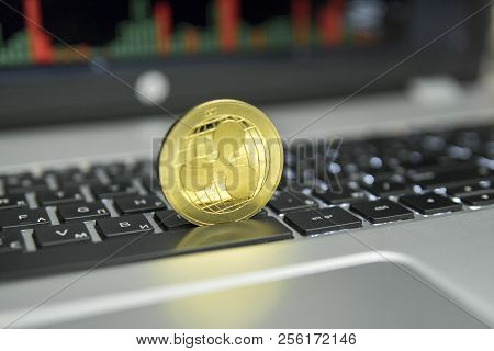 Golden Ripple Coin On A Black Keyboard Of Silver Laptop And Diagram Chart Graph On A Screen As A Bac